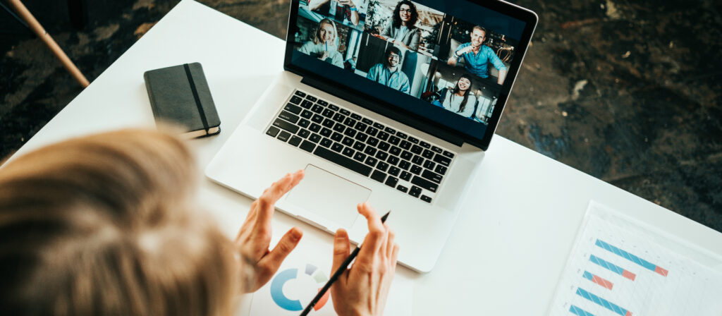 Woman has video call with her remote teammates using laptop. White loft workspace